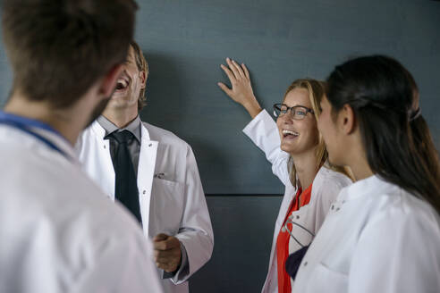Fröhliches männliches und weibliches Gesundheitspersonal bei einer Diskussion im Krankenhaus - BMOF00538