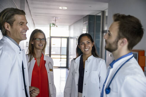 Medical team discussing while standing in corridor at hospital - BMOF00540