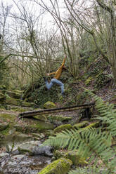 Unbekümmerter Mann springt über einen Steg im Wald - AFVF08456