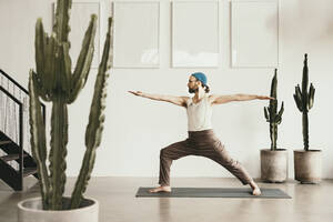 Männlicher Yogalehrer beim Üben mit ausgestreckten Armen - MJRF00362