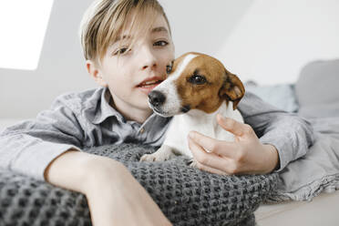 Junge mit Hund auf dem Bett zu Hause - KMKF01658