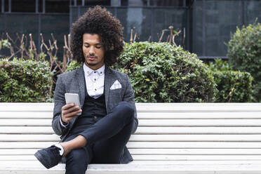 Handsome young businessman using mobile phone on bench - PNAF01291