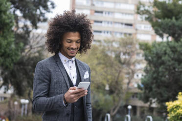 Handsome young businessman working on mobile phone in city - PNAF01295