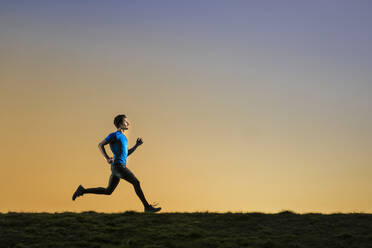 Sportler joggt mit Hingabe bei Sonnenuntergang - STSF02892
