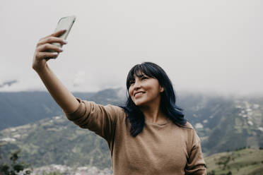 Lächelnd Mitte erwachsene Frau, die selfie durch Handy vor dem Himmel - DSIF00384