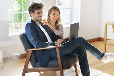 Smiling couple looking at laptop at home - SBOF03674