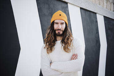 Hipster-Mann steht mit verschränkten Armen vor einer Wand - EBBF02991