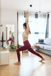 Mature woman practicing yoga while looking in mirror at home - MRRF00980