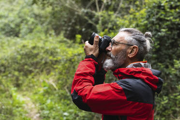 Männlicher Entdecker beim Fotografieren im Wald - PNAF01327