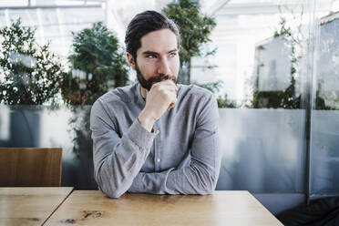 Thoughtful mid adult male entrepreneur at desk in office - EBBF03046