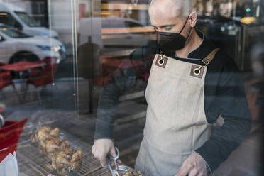 Reifer männlicher Restaurantbesitzer schneidet Brathähnchenfleisch in der Großküche - EGAF02217