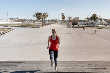 Woman jogging on steps in city during sunny day - AMPF00160