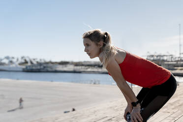 Thoughtful female jogger resting on pier - AMPF00161