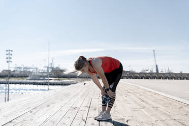 Junge Sportlerin ruht sich an einem sonnigen Tag auf dem Pier aus - AMPF00162