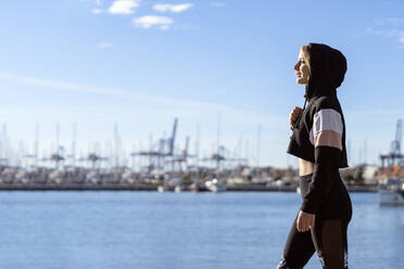 Nachdenkliche junge Frau, die wegschaut, während sie am Hafen steht - AMPF00171