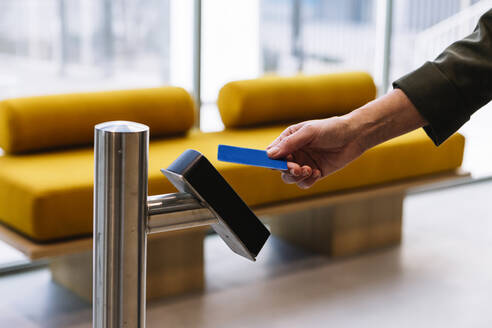 Woman holding ID card near reader while entering office - XLGF01388