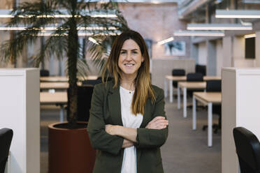 Businesswoman with arms crossed standing in office - XLGF01397