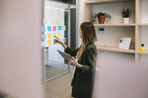 Eine Unternehmerin beim Brainstorming mit einem digitalen Tablet im Büro - XLGF01425