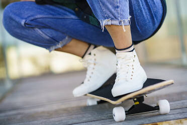 Woman crouching on skateboard - JSMF02087