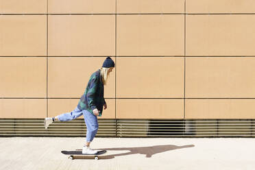 Junge Frau beim Skateboarden an einem sonnigen Tag - JSMF02091