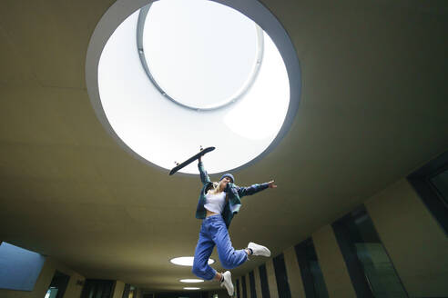 Young woman jumping under skylight - JSMF02099