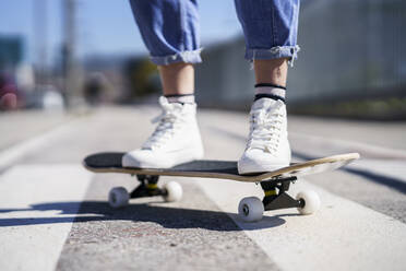 Woman standing on skateboard during sunny day - JSMF02106