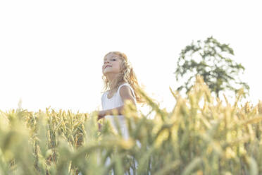 Smiling girl looking away while running amidst crop plants - WFF00523