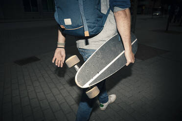 Niedriger Ausschnitt eines Mannes mit Skateboard und Rucksack auf dem Fußweg - MASF22528