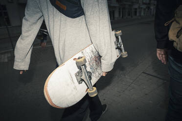 Männliche Freunde mit Skateboard auf dem Fußweg in der Abenddämmerung - MASF22529