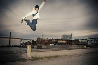 Mittlerer erwachsener Mann mit Skateboard springt gegen den Himmel - MASF22535