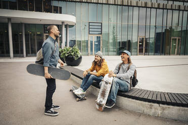 Smiling male friends talking with each other on footpath - MASF22551