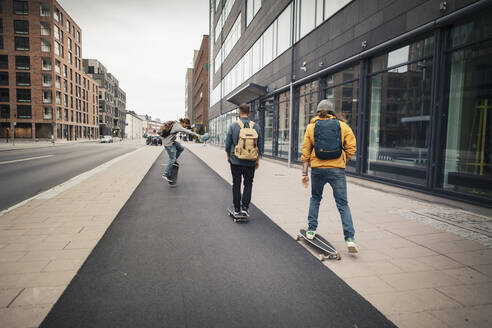 Männliche Freunde beim Schlittschuhlaufen auf dem Bürgersteig in der Stadt - MASF22556