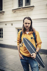Porträt eines Mannes mit Skateboard auf einem Fußweg - MASF22573