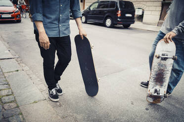 Niedriger Ausschnitt von männlichen Freunden mit Skateboard auf der Straße - MASF22580