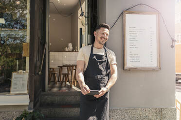 Lächelnder männlicher Unternehmer mit digitalem Tablet vor einem Cafe - MASF22635