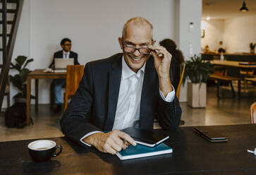 Porträt eines lächelnden männlichen Unternehmers mit Augen am Konferenztisch im Off - MASF22666