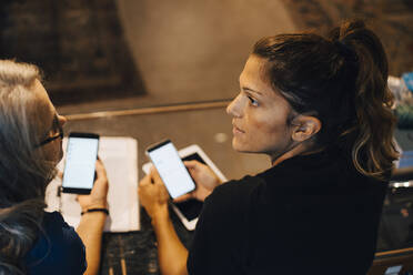 Weibliche Kollegen benutzen ein Smartphone in einem Einzelhandelsgeschäft - MASF22691