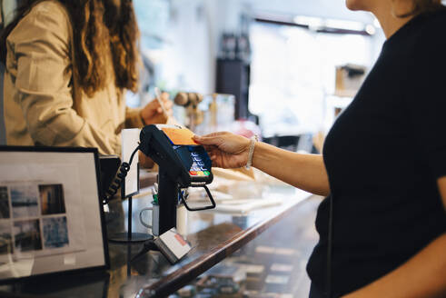 Ausgeschnittenes Bild eines männlichen Kunden, der mit seiner Kreditkarte an die Inhaberin eines Einzelhandelsgeschäfts zahlt - MASF22695