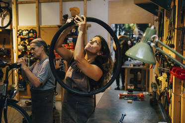 Female coworkers repairing bicycle at repair shop - MASF22724