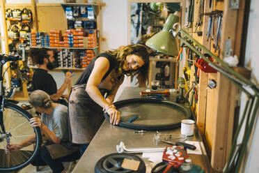 Male and female mechanics repairing bicycle in repair shop - MASF22726