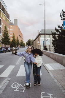 Teenager-Mädchen hilft ihrer Freundin beim Skaten auf der Straße in der Stadt - MASF22759