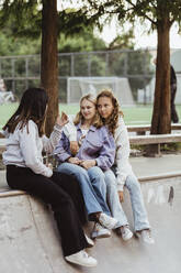 Teenage girl talking with female friends at skateboard park - MASF22767