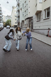 Weibliche Freunde genießen beim Gehen auf der Straße in der Stadt - MASF22807