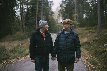 Homosexual couple talking with each other while standing amidst forest - MASF22828