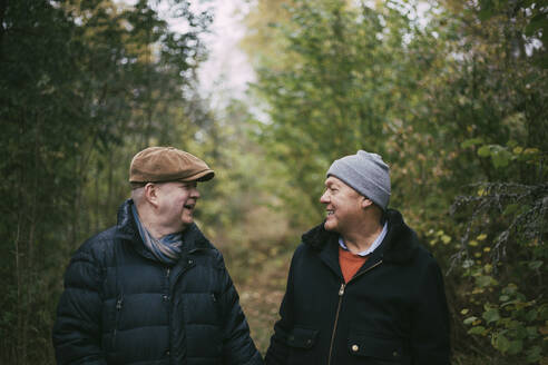 Lächelndes älteres homosexuelles Paar schaut sich im Wald an - MASF22835