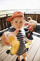 Porträt eines niedlichen Jungen, der Spielzeug gibt, während er an einem sonnigen Tag im Freien steht - MASF22893