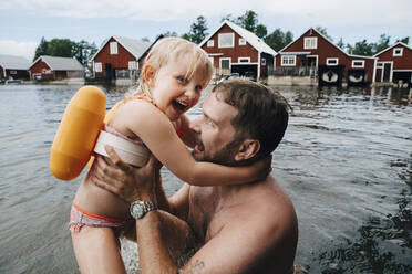 Portrait of cheerful daughter with father in lake during vacations - MASF22897