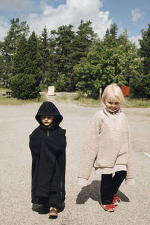 Brother and sister walking in park during sunny day - MASF22906