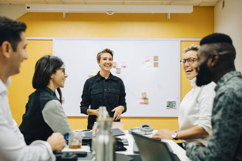 Business people laughing while discussing during meeting in board room - MASF22944