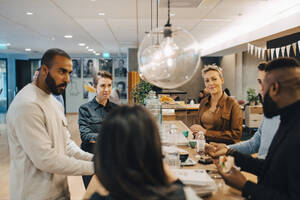 Männliche und weibliche Fachkräfte diskutieren während einer Besprechung in der Cafeteria im Büro - MASF22964
